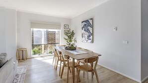 Una zona de menjador amb una taula de fusta, cadires, una planta en test i un quadre a la paret.