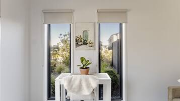 A room with a white table, a potted plant, and a framed picture on the wall.