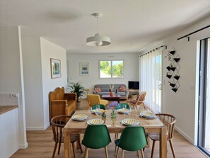 Comedor con una mesa de madera dispuesta para cuatro personas, rodeado de sillas verdes.