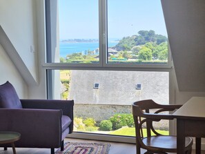 Um quarto com uma janela grande, um sofá, uma cadeira e uma mesa.