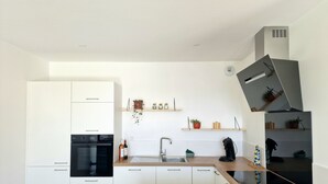 Eine moderne Küche mit weißen Schränken, einem schwarzen Backofen, einer Holz Arbeitsplatte, einer Spüle und einer eingebauten Dunstabzugshaube.