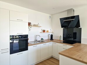 Una cocina moderna con armarios blancos, una estufa negra, un fregadero y una cafetera.