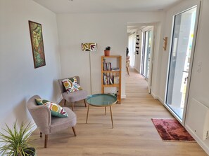 Una sala de estar moderna con un sofá, una mesita, una estantería y una planta en maceta.