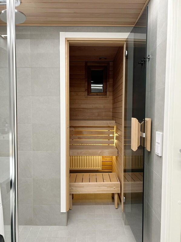 A sauna room with wooden benches and a glass door.