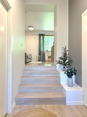 A staircase leading to a living area with a view of greenery outside.