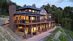 A two-story house with a balcony, stone pillars, and a driveway leading to the entrance. - Incredible Views *Arcade*Cinema*Sauna*Steamroom @ Peachtree Ridge (Boone)