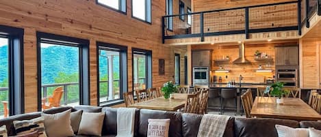 A spacious living area with a large sofa, a dining table, and a kitchen in the background.