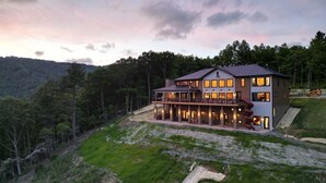 A large, two-story house with a balcony, surrounded by a forested hillside. - Incredible Views *Arcade*Cinema*Sauna*Steamroom @ Peachtree Ridge (Boone)
