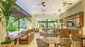 A modern interior with multiple seating areas, ceiling fans, and a kitchen area with a TV. - Spacious and luxurious 4-bedroom house Playa del Carmen with AC (Playa del Carmen)