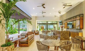 A modern interior with multiple seating areas, ceiling fans, and a kitchen area with a TV. - Spacious and luxurious 4-bedroom house Playa del Carmen with AC (Playa del Carmen)