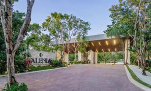 A modern building entrance with a sign reading 'ALENIA CLUB RESIDENCIAL,' surrounded by trees and a paved walkway. - Spacious and luxurious 4-bedroom house Playa del Carmen with AC (Playa del Carmen)