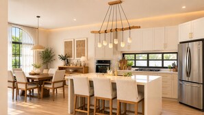A modern kitchen with a central island, stainless steel appliances, and a dining area with chairs and a table. - Spacious and luxurious 4-bedroom house Playa del Carmen with AC (Playa del Carmen)