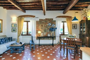 Uma sala de estar com sofá, mesa, cadeiras, lareira e parede de pedra.