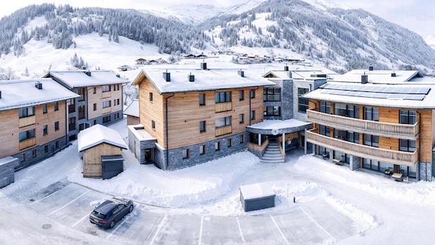 A modern ski resort with multi-story buildings, a parking area, and a mountainous backdrop. - Rauris Penthouse With Sauna (Rauris)