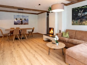A modern living room with a fireplace, wooden furniture, and a painting of a deer. - Spacious Holiday Home in Rauris (Rauris)