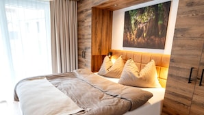 A modern bedroom with a large bed, wooden headboard, and a forest-themed wall art. - Rauris Penthouse With Sauna (Rauris)
