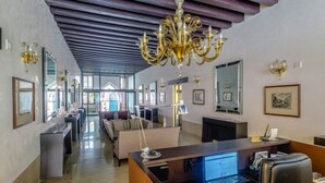 Een hotel lobby met een receptiebalie, een zithoek en een kroonluchter.