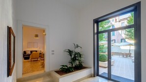 Een modern interieur met een trap naar een leefruimte, een grote glazen deur naar een terras en een pot met een plant.