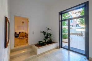 Ein modernes Interieur mit einer Treppe zu einem Wohnbereich, einer großen Glastür zu einer Terrasse und einem Blumentopf.