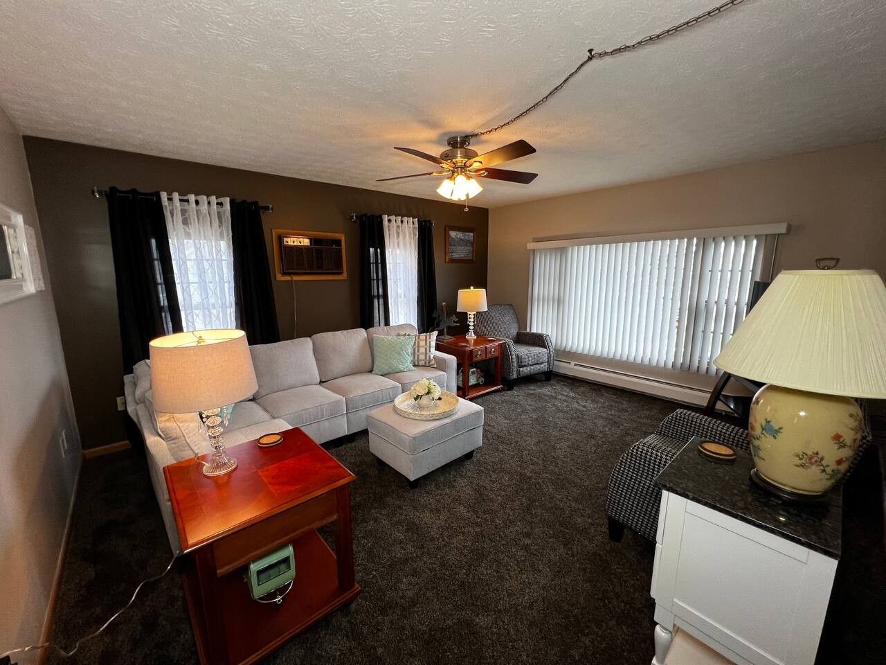 A living room with a sofa, a coffee table, a lamp, and a ceiling fan.