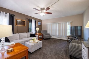 A living room with a sofa, armchair, coffee table, and television.