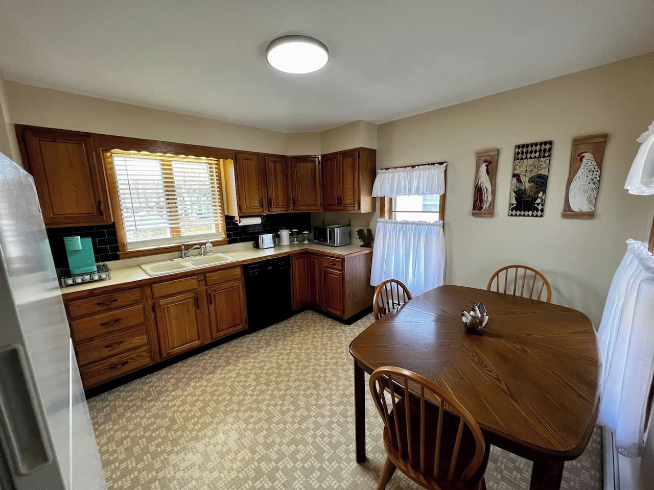 A compact kitchen with wooden cabinets, a dining table, and a refrigerator.