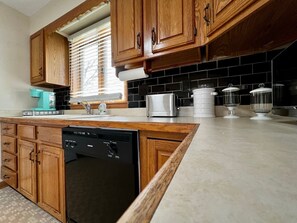 Une cuisine avec des meubles de rangement en bois, un lave-vaisselle, un four à micro-ondes et un évier.