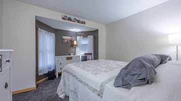 Un dormitorio con una cama, un aparador, un espejo y una lámpara.