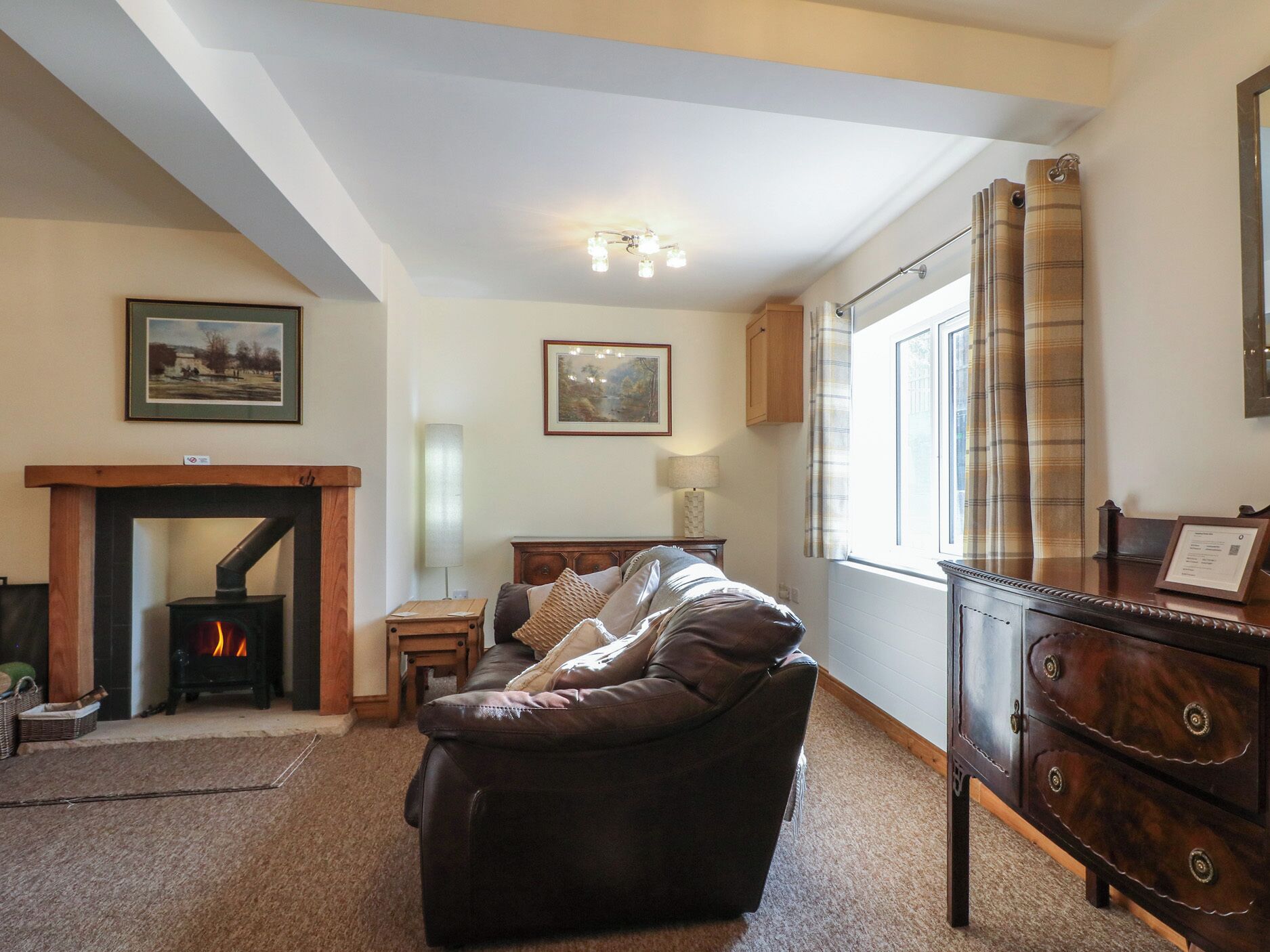 A living room with a fireplace, a sofa, a wooden cabinet, and a window with curtains.