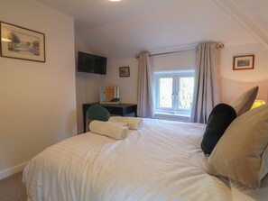 A bedroom with a bed, a desk, a chair, a television, and a window with curtains. - Rockhurst Farm (Matlock)