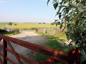 A rural road leading to a gate with a stone wall and a wooden fence. - Rockhurst Farm (Matlock)