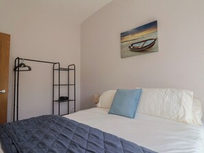 A bedroom with a bed, a wall-mounted shelf, and a painting of a boat on the wall. - Beck House (Weymouth)