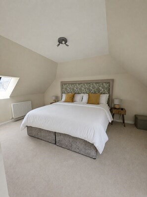 A bedroom with a large bed, a radiator, a nightstand, and a window.