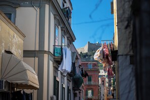 A narrow street with buildings on either side, balconies with hanging laundry, and a clear blue sky. - Charming apartment with terrace in the center of Napoli (Napoli)