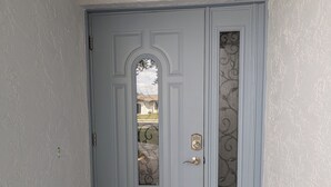 Una puerta azul claro con un panel de vidrio decorativo y una cerradura.