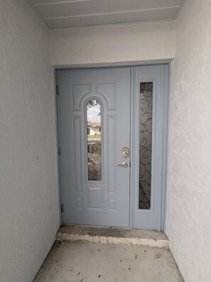 Una porta azzurra con un pannello di vetro decorativo e una serratura.