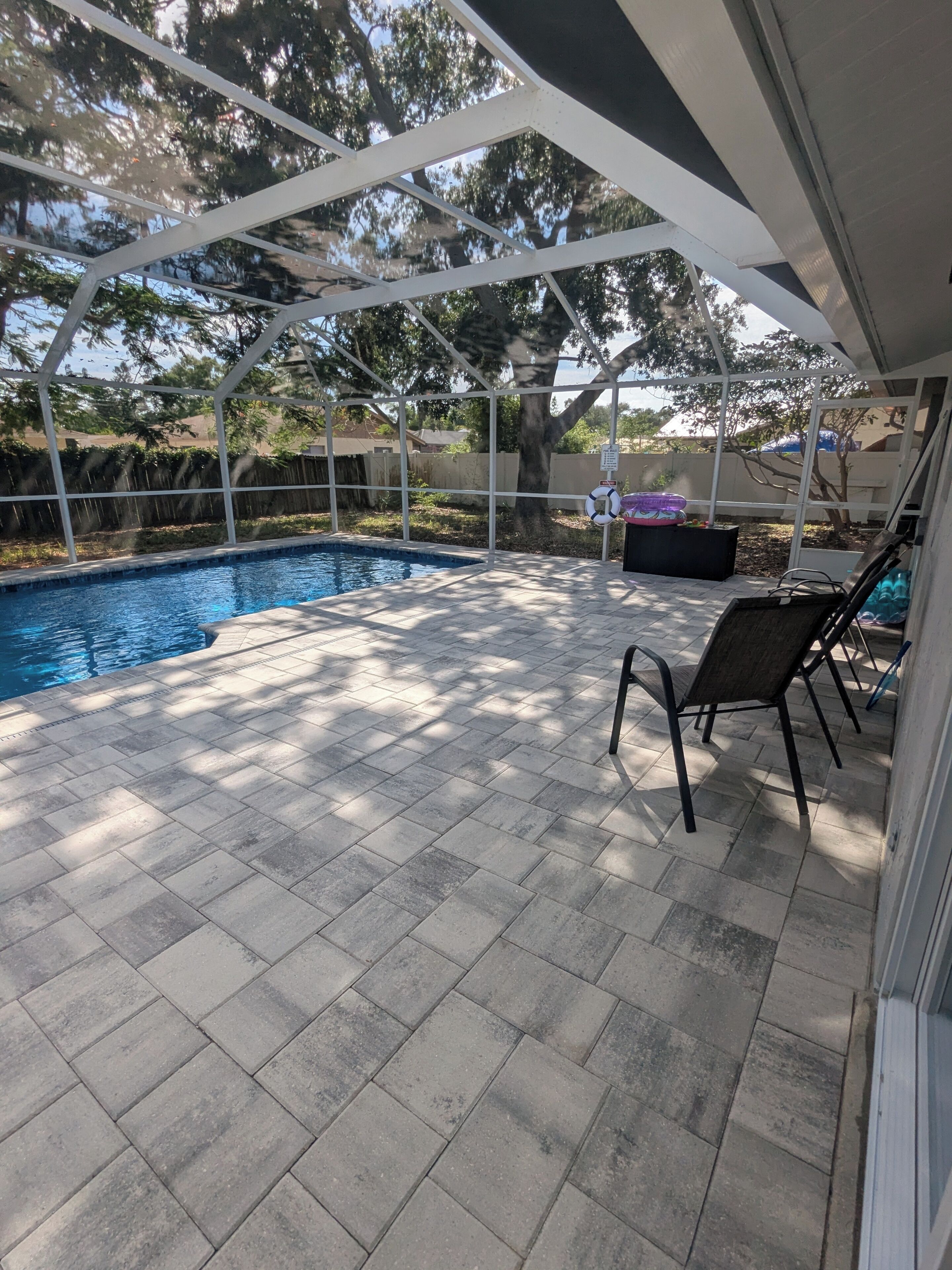 Un espace extérieur abrité comprenant une piscine, un sol carrelé et une chaise.