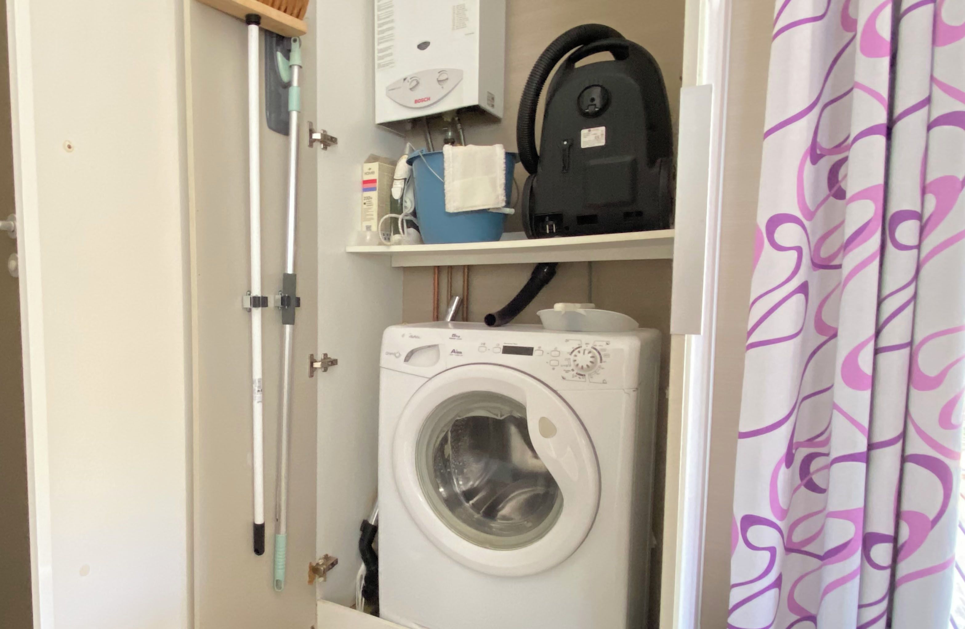 Une buanderie équipée d’un lave-linge, d’un sèche-linge et d’une étagère contenant divers objets.