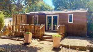 A wooden cabin with a deck, a sliding glass door, and a small outdoor seating area.