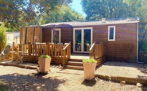 Una cabaña de madera con terraza, puerta corrediza de vidrio y un pequeño espacio de estar al aire libre.