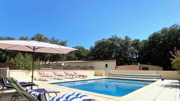 Une piscine avec des chaises longues et des parasols.
