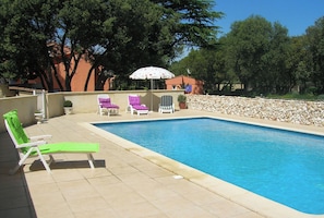 A swimming pool with lounge chairs and a stone wall.