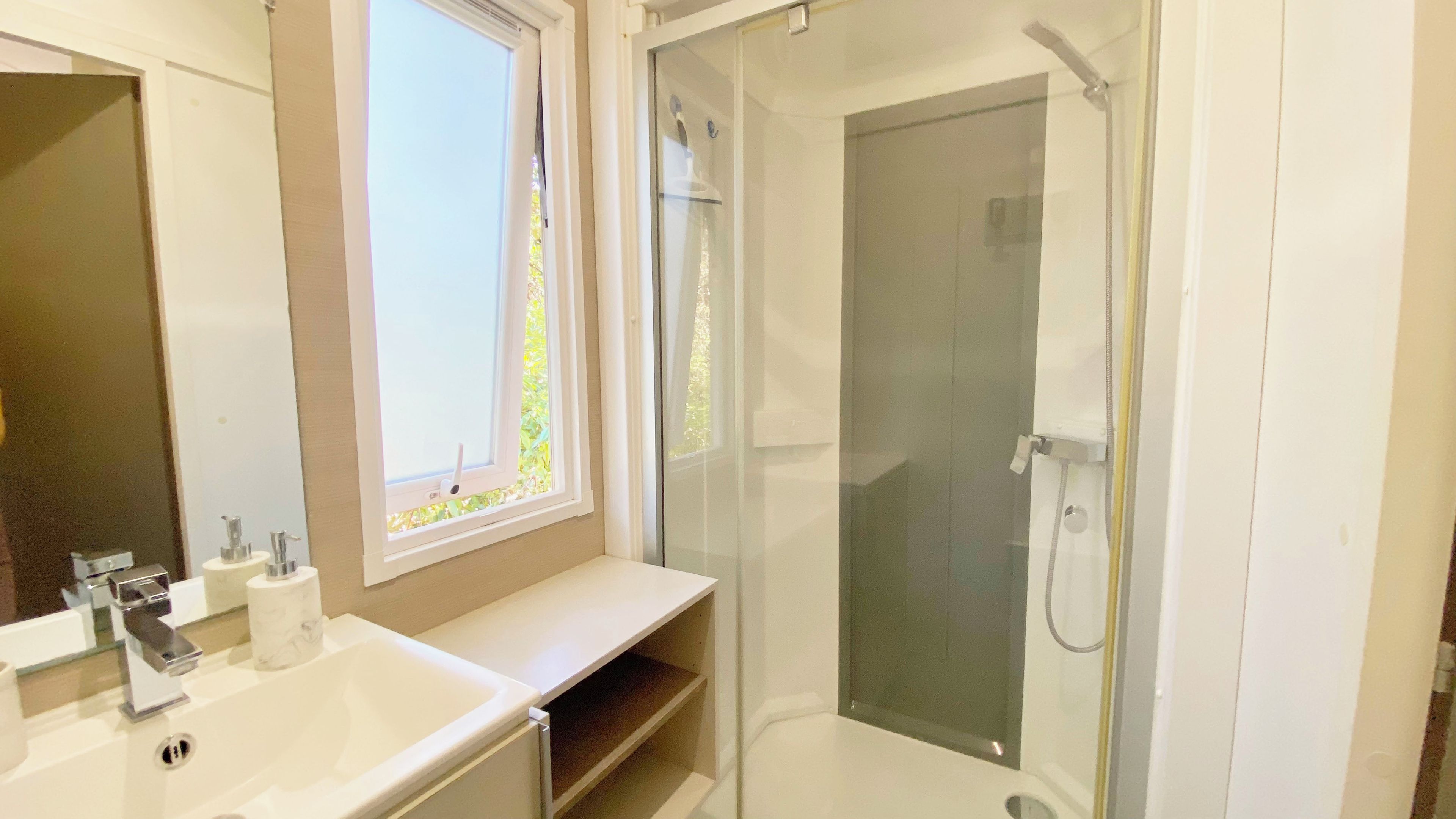 Une salle de bain avec une douche, un lavabo et une fenêtre.