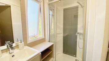 Une salle de bain avec une douche, un lavabo et une fenêtre.