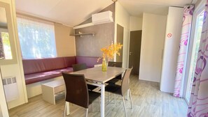 A compact living space with a dining table, chairs, a sofa, and a small kitchenette. - Bright Wooden Cottage with Pool near Uzès – Sleeps 4 (Saint-Siffret)