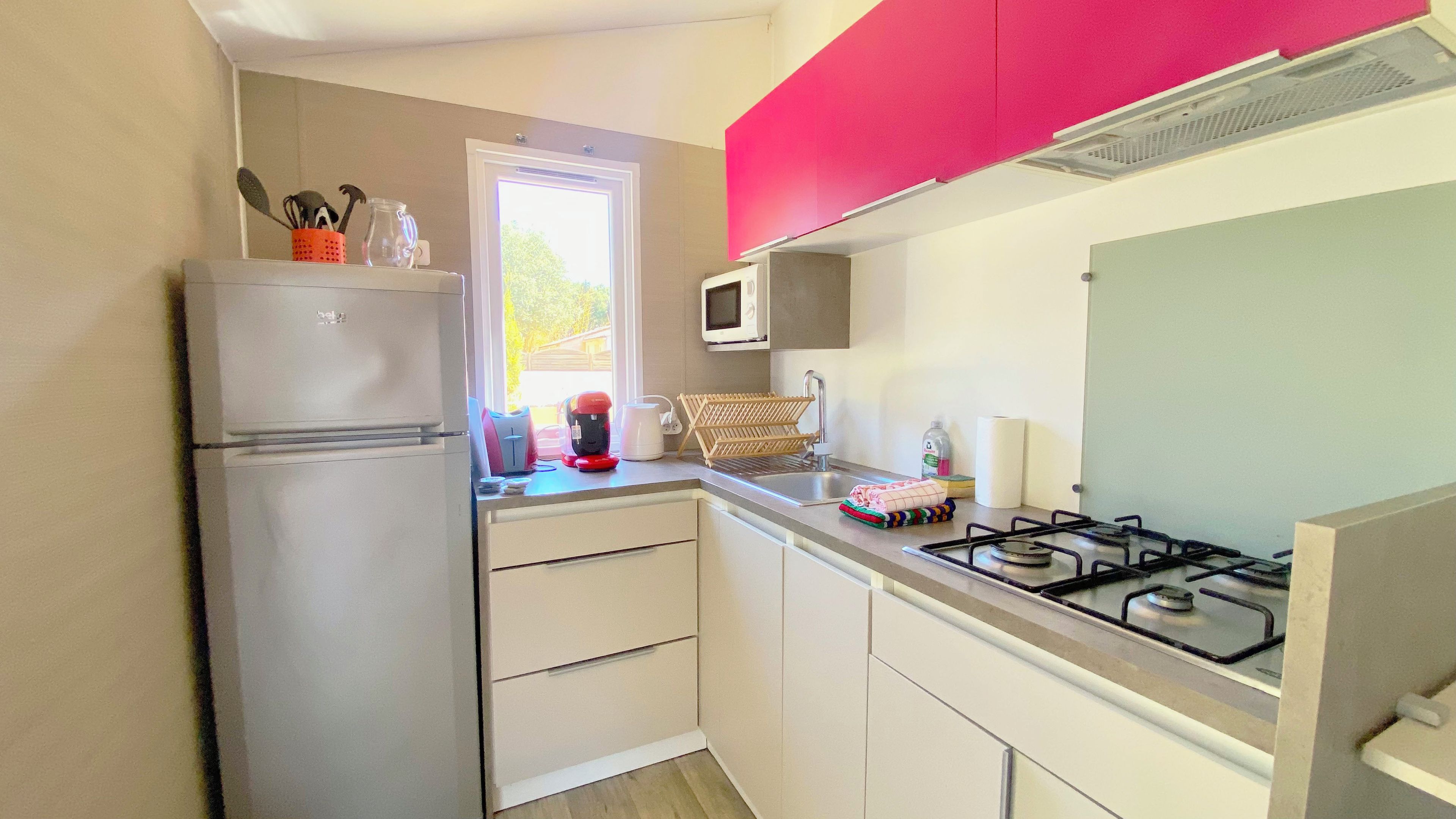 A compact kitchen with a refrigerator, microwave, and gas stove.