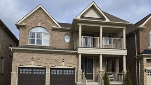 A two-story house with a front porch, two garages, and a landscaped lawn.