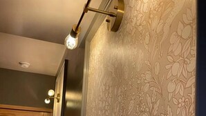 Ein Flur mit Holztür, strukturierten Tapeten und einer Wandleuchte.