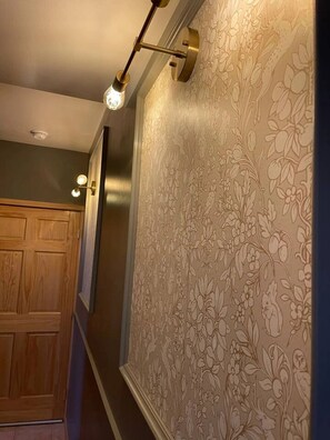 A hallway with a wooden door, patterned wallpaper, and a wall-mounted light fixture. - Romantic Twin Lakes lodge room with queen bed, porch & lake views (Twin Lakes)
