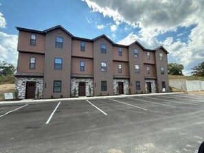 A multi-story building with a parking lot in front. - Willow Creek Townhouse (Aliquippa)